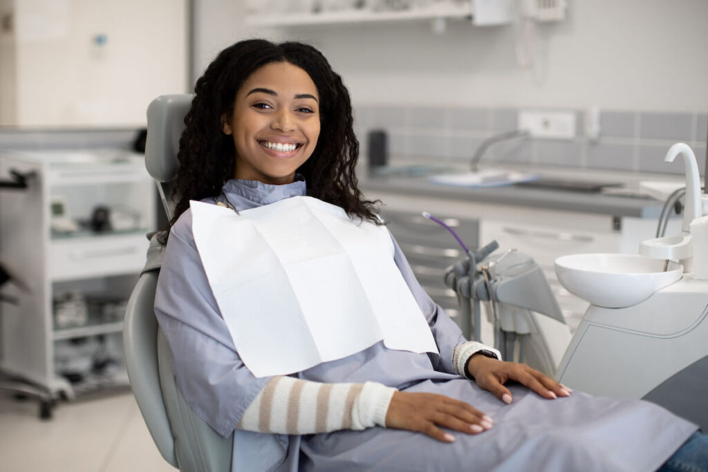 Dental services happy smiling black woman sitting - Oral Plastic Surgery & Periodontics