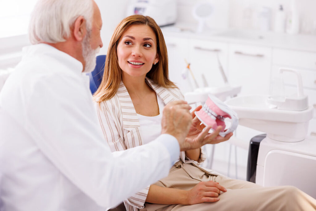 Dentist explaining procedure to patient on plastic - Oral Plastic Surgery & Periodontics