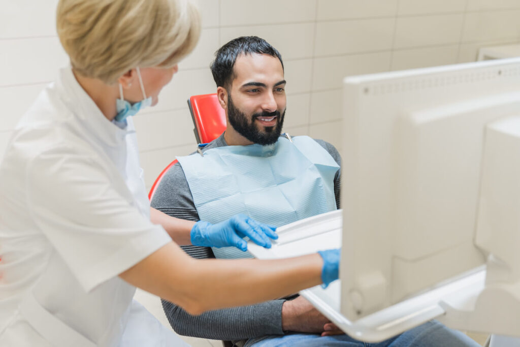 Dentist showing x-ray photo of jaws on computer - Oral Plastic Surgery & Periodontics