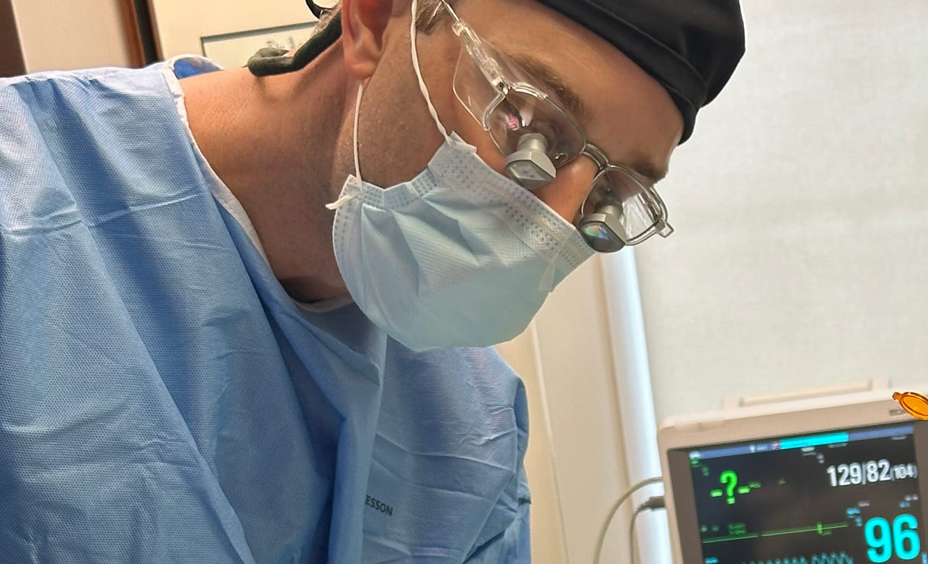 Dr Stephen B Hutton conducting esthetic periodontal surgery with surgical loupes and advanced monitoring equipment in La Jolla clinic